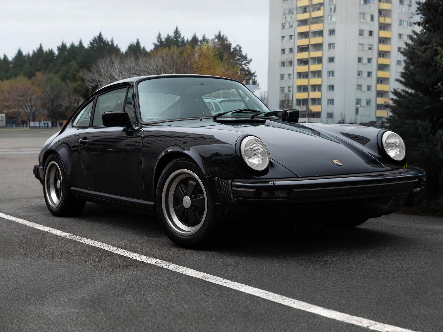 Schwarzer Porsche 911 (964) in Front-3/4-Ansicht auf freier Fläche